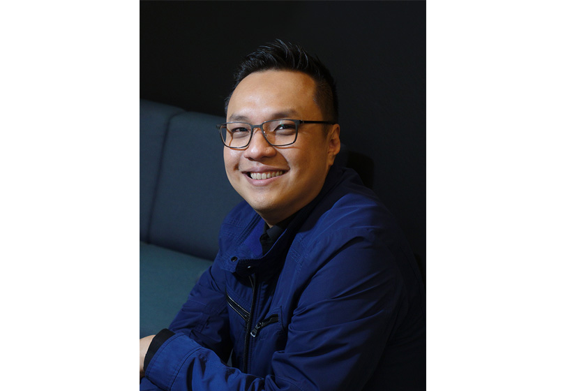 A man with glasses and blue jacket sitting on the sofa